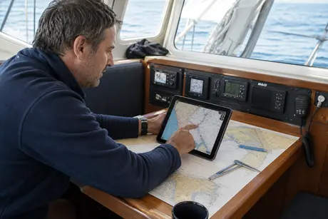 Plaisancier préparant une croisière sur une carte marine avec un smartphone